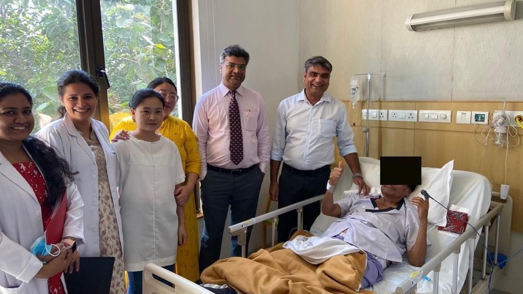 Family and doctors beside a recovering patient on the ward